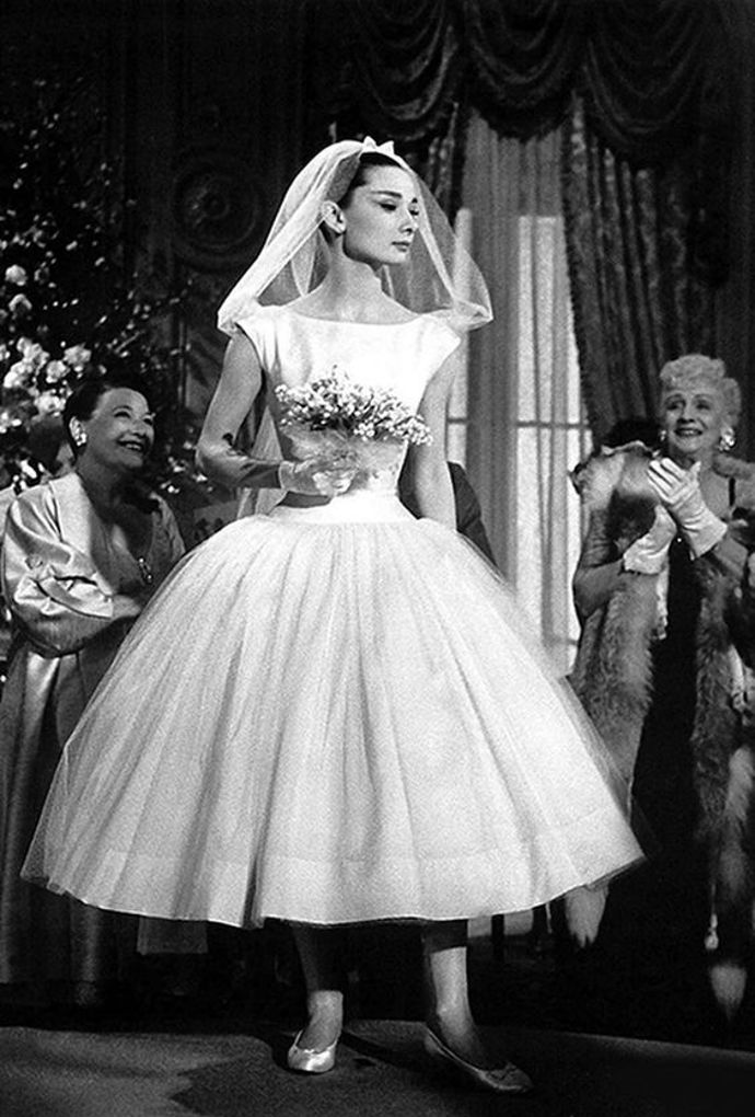 Usměvavá tvář / Funny Face

Šaty od Givenchy oblékla Jo (Audrey Hepburn) ve filmu Usměvavá tvář v roce 1957. Moderní midi délka a legendární Audrey – tyto šaty patří k nejznámějším ve filmové historii. Údajně se jimi inspirovala i Megan Markle, která si v roce 2018 brala prince Harryho v minimalistických šatech od návrhářky Clare Waight Keller z módního domu Givenchy. Nápadně podobná byla i Meganina svatební kytice!

