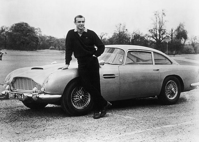 Sean Connery jako James Bond při natáčení bondovky Goldfinger se špionážním autem Aston Martin DB5 1964.
