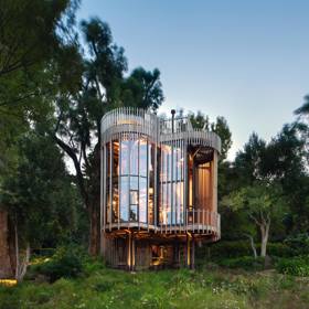  

Malan Vorster Treehouse, 2017

Ztracen v okolo rostoucí zeleni, Treehouse od jihoafrického studia Malan Vorster připomíná tajnou dětskou skrýš v koruně stromu. Přání investora, který měl na pozemku již rodinnou vilu, bylo získat samostatný a zcela oddělený prostor – útočiště, kde by mohl být zcela o samotě. Architekti zadání vyřešili formou čtyř vzájemně propojených válcových věží, vynesených na pilotech. Dřevěné lišty na fasádě propouštějí světlo, ale zároveň zajišťují potřebné soukromí. 

