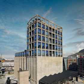  

Zeitz MOCAA, 2017

Kdysi nejvyšší budova subsaharské Afriky, silo v přístavu Kapského Města, dnes slouží jako muzeum současného afrického umění. Britský architekt Thomas Heatherwick proměnil dvaačtyřicet vysokých tubusů na uchování kukuřice na impozantní atrium s téměř katedrální atmosférou. Kolem atria umístil v několika patrech různě velké výstavní galerie a na střechu sochařskou zahradu. V exteriéru zaujmou rozměrná okna, jež svým vypouklým tvarováním naznačují obrovský tlak, jemuž bylo silo kdysi vystaveno. 
