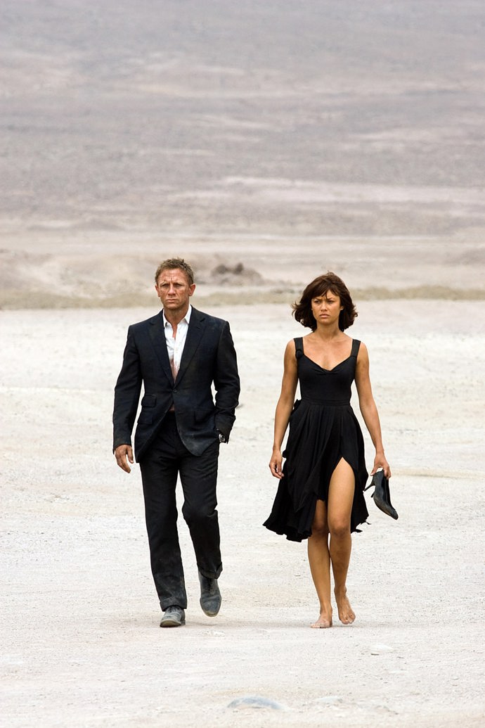 Olga Kurylenko jako Camille Montes v Quantum of Solace (2008) kráčí s Jamesem Bondem pouští, bosa a v malých černých.
Olga Kurylenko jako Camille Montes v Quantum of Solace (2008) kráčí s Jamesem Bondem pouští, bosa a v malých černých.