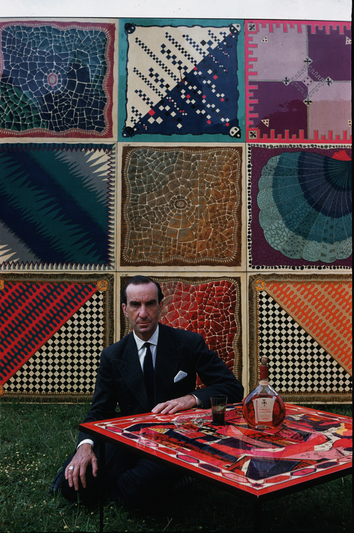 Florentský návrhář Emilio Pucci v roce 1959 u stolu s jedním z jeho návrhů spolu s dalšími ukázkami tisků.
