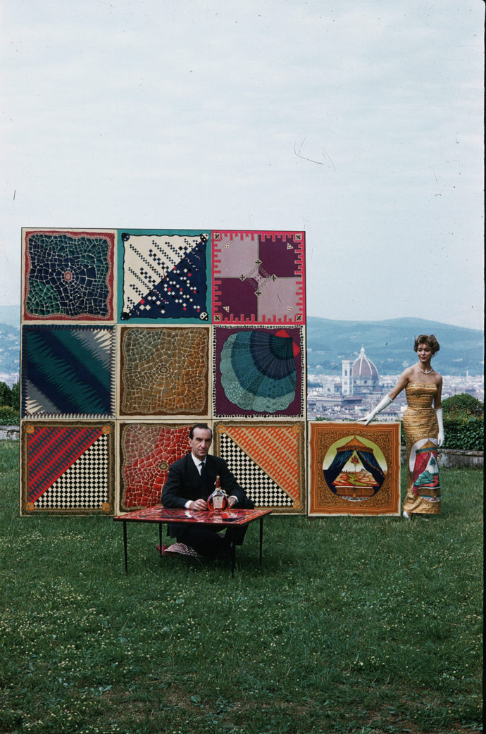 Florentský návrhář Emilio Pucci v roce 1959 u stolu s jedním z jeho návrhů spolu s dalšími ukázkami tisků.
