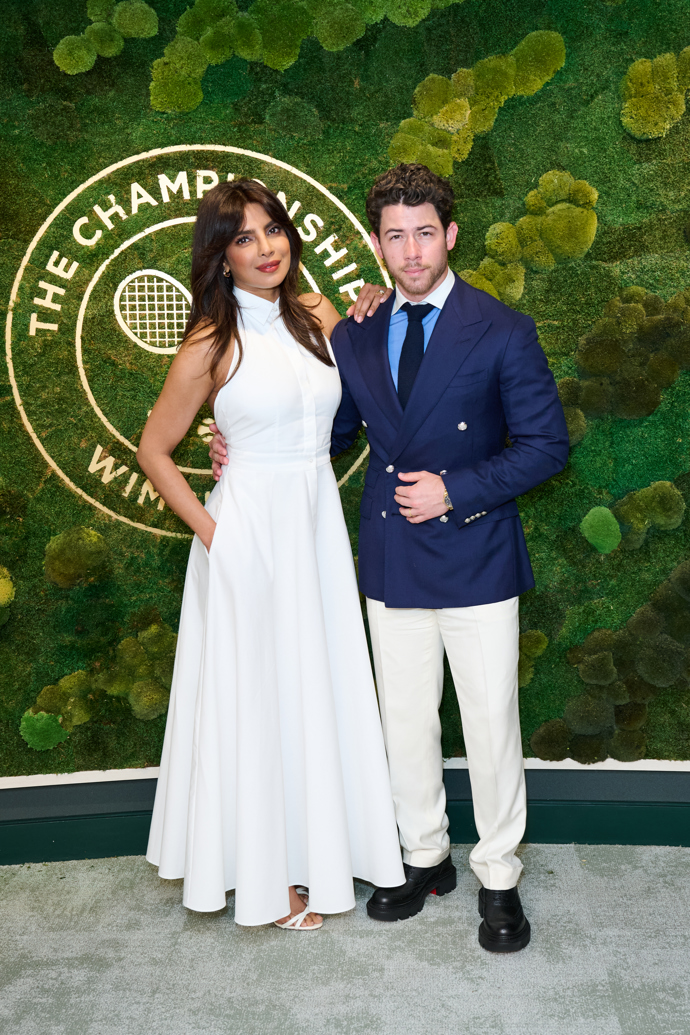  Priyanka Chopra a Nick JonasV ochozech kolem tenisových kurtů Wimbledonu pravidelně usedají i manželé Priyanka Chopra a Nick Jonas. Priyanka oblékla dlouhé bílé košilové šaty bez rukávů, Nick bílé kalhoty a k nim námořnicky modré sako přes modrou košili s bílým límečkem a tmavou kravatu. Trochu nepatřičně k lehkému sportovnímu outfitu vypadaly Nickovy černé boty s robustní podrážkou. 