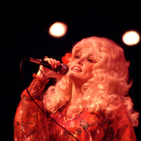 1977 – Hladce vyčesané, rozfoukané vlny doplněné hustými řasami a lesklými rty, epitom jižanského "tease-it-to-Jesus" glamouru. 1977 – Hladce vyčesané, rozfoukané vlny doplněné hustými řasami a lesklými rty, epitom jižanského "tease-it-to-Jesus" glamouru.