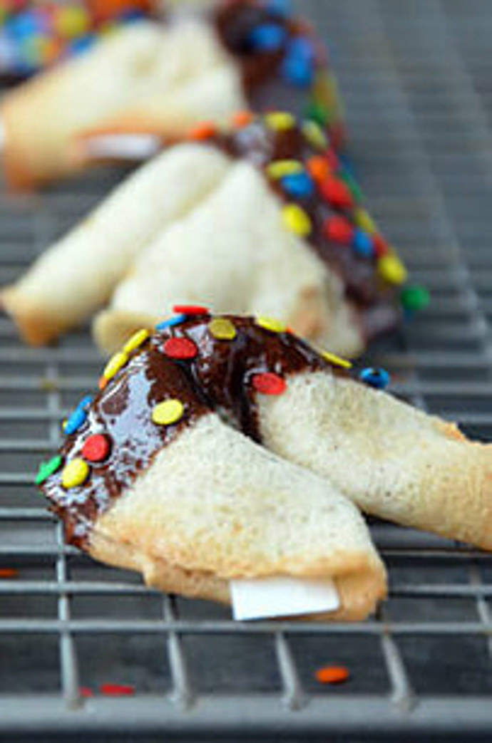 19. Upečte svým blízkým koláčky štěstí. Na 16 ks smícháme 4 bílky, 1/2 lžičky vanilkového extraktu, 1/4 lžičky skořice, 1/2 hrnku mouky a 1/2 hrnku cukru. Pomocí lžíce vylijeme těsto na pečící papír a vytvoříme velmi tenká kolečka. Pečeme při 180 °C cca 6 minut. Doprostřed vložíme lístek s přáním, pomocí špachtle kolečka v půli přehneme a stočíme okraje k sobě, aby vznikly rohlíčky. Dozdobíme čokoládou a cukrovým sypáním.