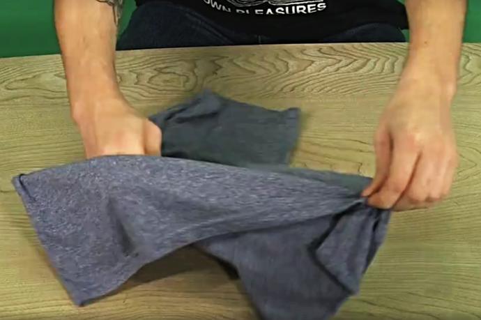 3. Teď už jen zbývá udělat magický pohyb. Překřížené ruce vraťte do přirozené polohy, trochu s tričkem zatřeste, aby se vyrovnalo, a přeložte jej.