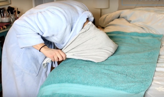 6. Jednou rukou je přidržíme, druhou přeložíme horní polovinu trika směrem ke krku a přitiskneme pomocí této ruky cípy pod trikem. Za neustálého tlaku trika na zadní část hlavy plynule uchopíme rukávy.