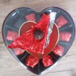 Čokoládová růže z tmavé čokolády s náplní z višní v alkoholu v retro obalu. Cena srdce 106 g je 70 Kč.