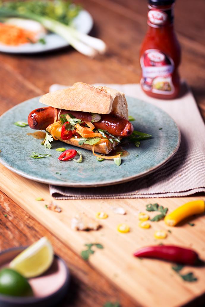 Asijský hot dog

Suroviny:

4 kvalitní vepřové klobásky 
4 sezamové bagetky 
snítky čerstvého koriandru 
jarní cibulku 
čerstvou chilli papričku 
Sladko-kyselou omáčku Spak 
šťávu z půlky limetky 
1 větší mrkev 

Postup: 

Do sladko-kyselé omáčky Spak přidáme nasekaný čerstvý koriandr, na tenká kolečka nakrájenou jarní cibulku a šťávu z limetky, to vše společně promícháme. Bagetky si podélně nakrojíme a opečeme ze všech stran, poté do nich vložíme klobásky, na které přidáme naši omáčku, a nakonec posypeme na tenoučké nudličky nakrájenou mrkev, nasekanou čerstvou chilli papričku a pár lístečků čerstvého koriandru.