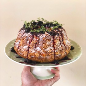 Kynutá bábovka s mandlemi a borůvkami:

Suroviny:

60 g rozinek
300 g Pernerka BIO špaldová mouka jemná
40 g cukru krupice
3 ks žloutků
100 g mléka
8 g droždí
70 g másla
5 g mořské soli.

Na dokončení: borůvkový džem, čerstvý tymián, cukr moučka.

Postup:

Do mísy navážíme všechny ingredience kromě rozinek a vařechou vymícháme hladké lesklé těsto. Není třeba přidávat žádnou mouku; těsto odpočinkem “zpevní”. Rozinky vmísíme na úplný konec. Necháme přikryté na teplém místě kynout. Bábovkovou formu vytřeme polotekutým máslem a vysypeme hoblovanými mandlemi. Vykynuté těsto krátce propracujeme a uválíme bochánek. V něm uděláme díru (jako na donut) a opatrně umístíme do připravené formy. Necháme kynout do trojnásobného objemu. Upečeme ve vyhřáté troubě asi 20 minut při 170 stupních C.