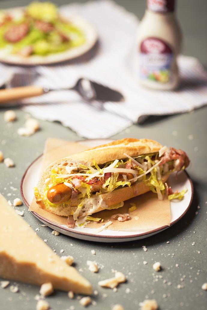 Caesar hot dog

Suroviny:

4 nožičky kvalitních krůtích klobásek 
4 francouzské bagetky 
10 dkg anglické slaniny 
1/2 římského salátu lžíci majonézy 
75% natur Spak 80 ml Caesar dressingu Spak 10 dkg parmezánu 
6 filetů z ančoviček šťávu z půlky citrónu 

Postup: 

Slaninu nakrájíme na proužky a opečeme do křupava. Majonézu a Caesar dressing Spak si dáme do misky, přidáme citrónovou šťávu, najemno nastrouhaný parmezán, filetky z ančoviček a vše tyčovým mixérem rozmixujeme. Poté si nadrobno nakrájíme římský salát a smícháme ho s naším dressingem. Bagetky si podélně nakrojíme a opečeme ze všech stran, vložíme do nich párky, na které položíme římský salát smíchaný s dressingem, a nakonec posypeme orestovanou slaninou.