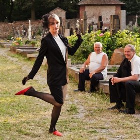 Všichni jsou smutní, nebo tak aspoň vypadají. Za zdí hřbitova zastavil starší mercedes a z něj vystupuje rovněž zestárlá „hérečka" Irenka. Pozoruje pohřeb přes zeď, dovnitř se neodváží. Odjede před koncem obřadu.