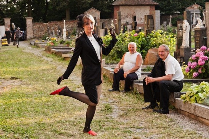 Všichni jsou smutní, nebo tak aspoň vypadají. Za zdí hřbitova zastavil starší mercedes a z něj vystupuje rovněž zestárlá „hérečka" Irenka. Pozoruje pohřeb přes zeď, dovnitř se neodváží. Odjede před koncem obřadu.