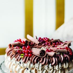 Vánoční Pavlova:

Suroviny:

Základ:
150 g moučkový cukr
150 g bílek (asi z 5 vajec)
1 lžička citronová šťáva
20 g kakao
30 ml černá káva
150 g cukr krupice.

Krém:
500 ml smetana ke šlehání
100 g hořká čokoláda (ideálně 70%)
50 g džem (brusinkový)
15 g kakao
40 g cukr krupice.

Na ozdobení:
čokoládové hoblinky
pistácie
červený rybíz
sušené brusinky.

Postup:

Den předem za stálého míchání svařte smetanu s cukrem, kakaem a džemem. Stáhněte z plotny a přidejte čokoládu. Nechte odstát. Až povolí, vyšlehejte hladký krém a nechte přes noc v ledničce.

Troubu zapněte na 120 °C. Bílky vyšlehejte s trochou citronové šťávy skoro dotuha. Pak po lžících všlehejte krupicový cukr. Hotový sníh je pevný a lesklý.

Moučkový cukr prosejte s kakaem a spolu s kávou metličkou opatrně vmiste do sněhu.

Na pečicí papír si nakreslete kruh o průměru 24 cm. Sáček s velkou hvězdicovou zdobicí trubičkou naplňte sněhem a nastříkejte po obvodu kruhu ve dvou barevných vrstvách. Pečte 80 minut a nechte vychladnout v troubě.

Smetanu vyšlehejte. Pavlovu přendejte na servírovací tác a pomocí stejné trubičky na ni nastříkejte šlehačku. Ozdobte brusinkami, rybízem, pistáciemi a čokoládou.