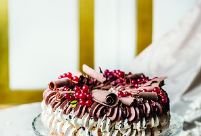 Vánoční Pavlova:

Suroviny:

Základ:
150 g moučkový cukr
150 g bílek (asi z 5 vajec)
1 lžička citronová šťáva
20 g kakao
30 ml černá káva
150 g cukr krupice.

Krém:
500 ml smetana ke šlehání
100 g hořká čokoláda (ideálně 70%)
50 g džem (brusinkový)
15 g kakao
40 g cukr krupice.

Na ozdobení:
čokoládové hoblinky
pistácie
červený rybíz
sušené brusinky.

Postup:

Den předem za stálého míchání svařte smetanu s cukrem, kakaem a džemem. Stáhněte z plotny a přidejte čokoládu. Nechte odstát. Až povolí, vyšlehejte hladký krém a nechte přes noc v ledničce.

Troubu zapněte na 120 °C. Bílky vyšlehejte s trochou citronové šťávy skoro dotuha. Pak po lžících všlehejte krupicový cukr. Hotový sníh je pevný a lesklý.

Moučkový cukr prosejte s kakaem a spolu s kávou metličkou opatrně vmiste do sněhu.

Na pečicí papír si nakreslete kruh o průměru 24 cm. Sáček s velkou hvězdicovou zdobicí trubičkou naplňte sněhem a nastříkejte po obvodu kruhu ve dvou barevných vrstvách. Pečte 80 minut a nechte vychladnout v troubě.

Smetanu vyšlehejte. Pavlovu přendejte na servírovací tác a pomocí stejné trubičky na ni nastříkejte šlehačku. Ozdobte brusinkami, rybízem, pistáciemi a čokoládou.