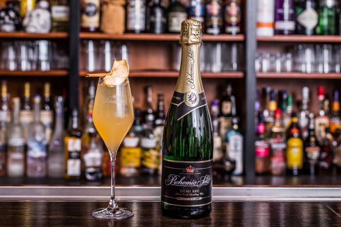 Cloudy Bubbles

Jednoduchý koktejl, který díky přidaným bublinám okouzlí hlavně hosty vánočních večírků, ale zároveň se hodí i k domácí pohodě. Pětinásobný Barman roku Martin Vogeltanz se při jeho vymýšlení nechal inspirovat oblíbenými a snadno dostupnými podzimními surovinami, jako je jablečný mošt a skořice, které doplnil šumivým vínem pro zjemnění chuti. Pokud si dáváte zrovna pauzu od alkoholu, vyzkoušejte verzi bez rumu a s nealkoholickým Bohemia Sektem.

•	2 cl světlý rum
•	1 cl medová voda
•	5 cl jablečný mošt
•	5–6 cl Bohemia Sekt demi sec
•	Sušené jablko a skořice na ozdobu

Postup: V kalíšku se středně teplou vodou rozpustíme lžičku medu v poměru 1:1. Připravenou sklenici na stopce naplníme ledem. Postupně přiléváme světlý rum, jablečný mošt a medovou vodu. Do hotového základu pomalu doléváme Bohemia Sekt demi sec. Nápoj opatrně promícháme tak, aby se všechny ingredience spojily. Na závěr dozdobíme plátkem sušeného jablka a skořicí. 

Tip barmana Martina Vogeltanze: Pro dosažení originální chuti koktejlu se určitě vyhněte použití jablečného džusu, který má jinou konzistenci i příchuť než mošt.
