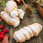 Kremrole:
Suroviny:
250 g máslo
250 g šlehačka
450 g špaldová hladká mouka
1/2 lžičky soli.
Sníh:
4 bílky
250 g cukr krupice
1 lžíce citronové šťávy.
Na dokončení:
1 vejce
50 g cukr moučka.
POSTUP:
Z másla, mouky a soli uděláme drobenku, do které přidáme vychlazenou smetanu a rychle zpracujeme v těsto. Necháme v chladničce asi 1 hodinu odpočinout. Poté vyválíme na pomoučněném vále na sílu asi 3 mm, nakrájíme rádýlkem či nožem na stejně silné proužky, potřeme vajíčkem a jednotlivé pruhy natáčíme na plechová tvořítka na trubičky. Pečeme v rozehřáté troubě při 180 °C asi 25 až 30 minut. Ještě vlažné sejmeme z tvořítek a necháme dobře vychladnout. Ve vodní lázní či mikrovlnce nahřejeme za stálého míchání bílky, cukr a citronovou šťávu do horka, dokud se krystalky zcela nerozpustí. Poté ušleháme do pevného nadýchaného sněhu. Sněhem naplníme cukrářský sáček s ozdobnou špičkou a kremrole jím naplníme. Před podáváním pocukrujeme.