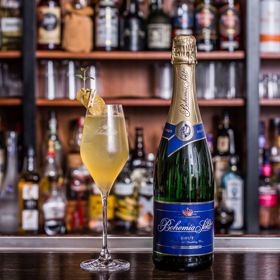 Sharp company

Koktejl sladkokyselé chuti se štiplavým závěrem udělá velký dojem. Díky zázvoru je ideální jak pro sychravé večery, tak i jako koření předvánočních a silvestrovských večírků. Jeho příprava je sice náročnější a vyžaduje použití šejkru, za vynaložené úsilí vám bude odměnou koktejl jako od profesionála.

•	2 cl Bourbon
•	1 cl čerstvá citronová šťáva
•	2 cl medová voda
•	3 plátky zázvoru
•	5–6 cl Bohemia Sekt brut
•	Kandovaný zázvor a tymián na ozdobu

Postup: Čerstvý zázvor rozmixujme tyčovým mixérem nebo rozdrtíme v hmoždíři. Poté dáme do šejkru a postupně přiléváme bourbon, medovou vodu a citronovou šťávu. K surovinám přidáme kostky ledu a šejkrujeme. Abychom vyloučili zbytky zázvoru, důkladně cedíme přes sítko. Hotový základ přelijeme do sklenice na stopce a pomalu dolijeme sektem a opatrně promícháme. Na závěr ozdobíme kandovaným zázvorem a tymiánem.

Tip Martina Vogeltanze: Intenzitu jednotlivých chutí si každý může vyladit dle svých preferencí. Pro milovníky kouřových chutí doporučuji nahradit bourbon kouřovou skotskou whisky.  

