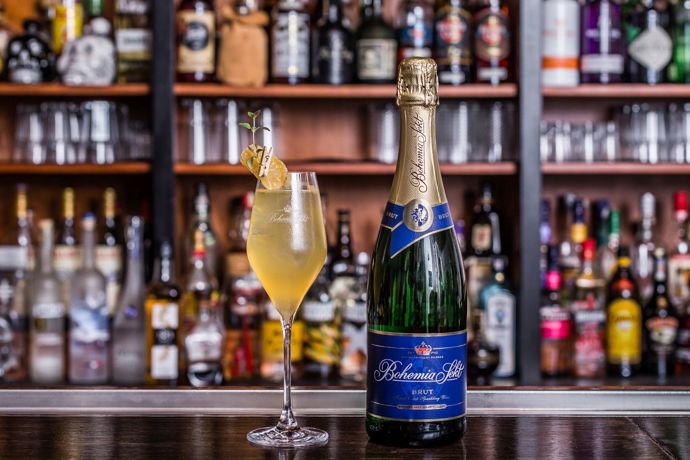 Sharp company

Koktejl sladkokyselé chuti se štiplavým závěrem udělá velký dojem. Díky zázvoru je ideální jak pro sychravé večery, tak i jako koření předvánočních a silvestrovských večírků. Jeho příprava je sice náročnější a vyžaduje použití šejkru, za vynaložené úsilí vám bude odměnou koktejl jako od profesionála.

•	2 cl Bourbon
•	1 cl čerstvá citronová šťáva
•	2 cl medová voda
•	3 plátky zázvoru
•	5–6 cl Bohemia Sekt brut
•	Kandovaný zázvor a tymián na ozdobu

Postup: Čerstvý zázvor rozmixujme tyčovým mixérem nebo rozdrtíme v hmoždíři. Poté dáme do šejkru a postupně přiléváme bourbon, medovou vodu a citronovou šťávu. K surovinám přidáme kostky ledu a šejkrujeme. Abychom vyloučili zbytky zázvoru, důkladně cedíme přes sítko. Hotový základ přelijeme do sklenice na stopce a pomalu dolijeme sektem a opatrně promícháme. Na závěr ozdobíme kandovaným zázvorem a tymiánem.

Tip Martina Vogeltanze: Intenzitu jednotlivých chutí si každý může vyladit dle svých preferencí. Pro milovníky kouřových chutí doporučuji nahradit bourbon kouřovou skotskou whisky.  

