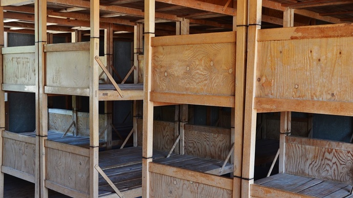 Jednoduchá dřevěná lůžka na ubytovnách v Dachau. Zatímco tábor byl projektován pro přibližně pět tisíc vězňů, při osvobození jich zde bylo více než 30 000...