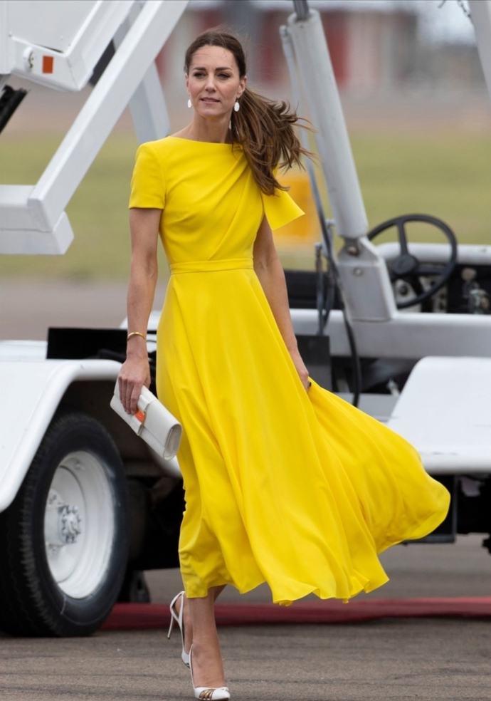 Kate Middleton v okouzlujících žlutých šatech, bílých lodičkách se zlatým detailem a bílým psaníčkem. Pokud byste si takový outfit, který je na jaro a léto jako stvořený, chtěla také pořídit, na českých e-shopech byste za něj zaplatila 4952 Kč.