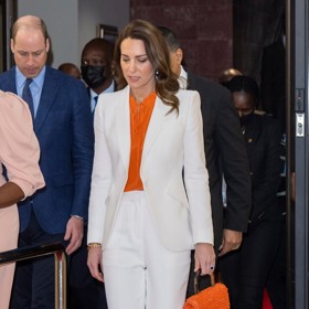 Kate Middleton v elegantním bílém kalhotovém kostýmku, který zkombinovala s oranžovou halenkou a bílými lodičkami do špičky. Na českých e-shopech byste za podobný outfit utratila okolo 4606 Kč.