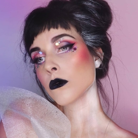 Netradiční make-up doplněný o blyštivé glittery a černou rtěnku.