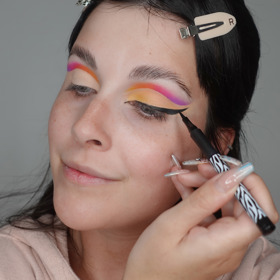 Po nanesení jemně broskvového stínu přes korektor vytvořte kočičí linku, která vede od vnitřního koutku oka.
