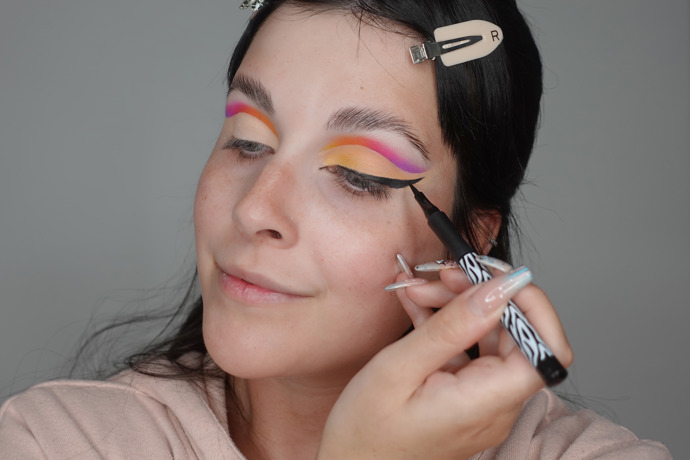 Po nanesení jemně broskvového stínu přes korektor vytvořte kočičí linku, která vede od vnitřního koutku oka.
