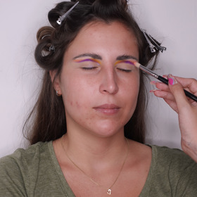 "Začala jsem líčením očí, pro které jsem vybrala zářivé letní odstíny. Nanesla jsem podkladovou bázi a zafixovala ji pudrem. Na vykreslení ohybu víčka jsem použila fialovou tekutou linku a následně ji rozpracovala fialovým stínem. Dále jsem nanesla žlutý a broskvový stín, abych dodala líčení duhový nádech. Na víčko jsem použila korektor, abych vykreslila precizní cut crease. Následně jsem na celou plochu pohyblivého víčka nanesla ještě zářivě růžový matný stín."