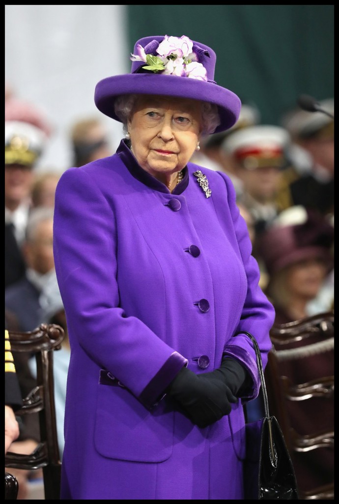 Královna Alžběta II. ve fialovém kabátku a klobouku. 