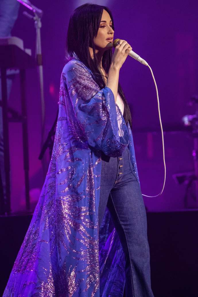 Zpěvačka Kacey Musgraves na jednom ze svých vystoupení v dlouhém fialovém kardiganu.