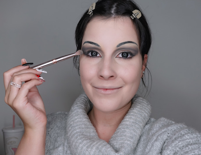 Pro stínování očí jsem použila především šedé a černé stíny, abych vytvořila dramatické líčení. Nebojte se stíny vytáhnout až k nově nakreslenému obočí. Korektorem jsem potom opticky zvětšila oční víčko pomocí techniky cut crease a nanesla na něj světlý perleťový stín. 