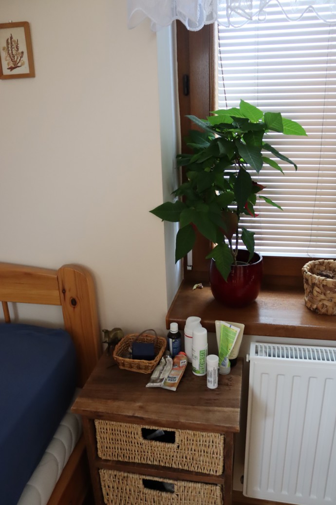 Naproti štendru s oblečením se nachází Hančina postel s nočním stolkem.