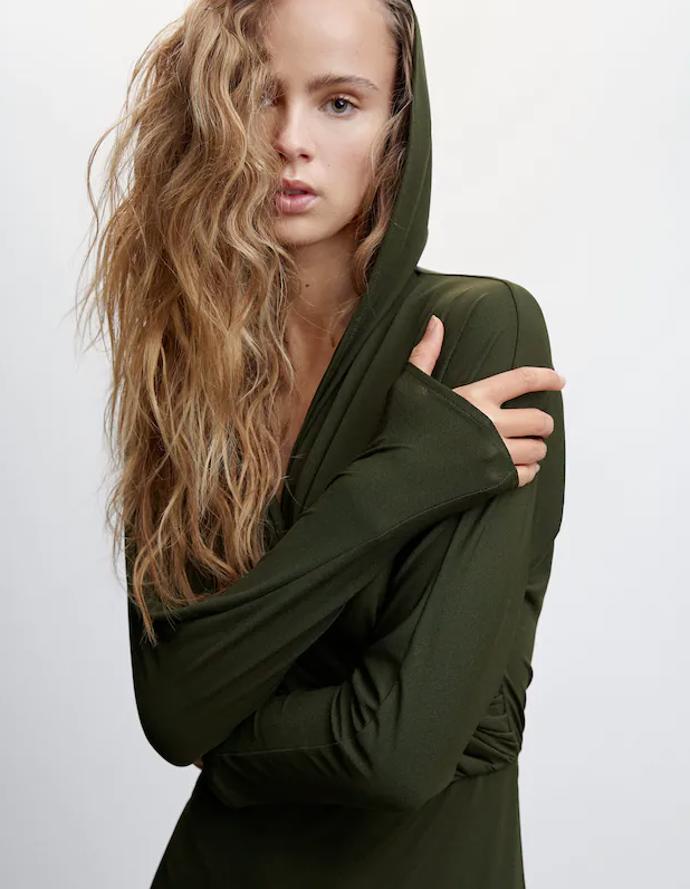 Kapuce proniká i do jiných dimenzí formální módy. Šaty Mango (999 Kč) které ozvláštnila, působí díky lehkému materiálu křehce a elegantně.