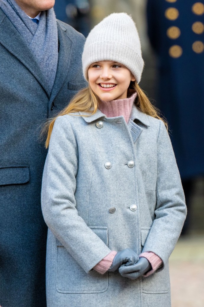 A další parádní zimní outfit. Estelle na oslavě svátku korunní princezny Victorie v kašmírovém svetru Bonpoint v lososové barvě a šedém dvouřadém kabátu stejné značky.