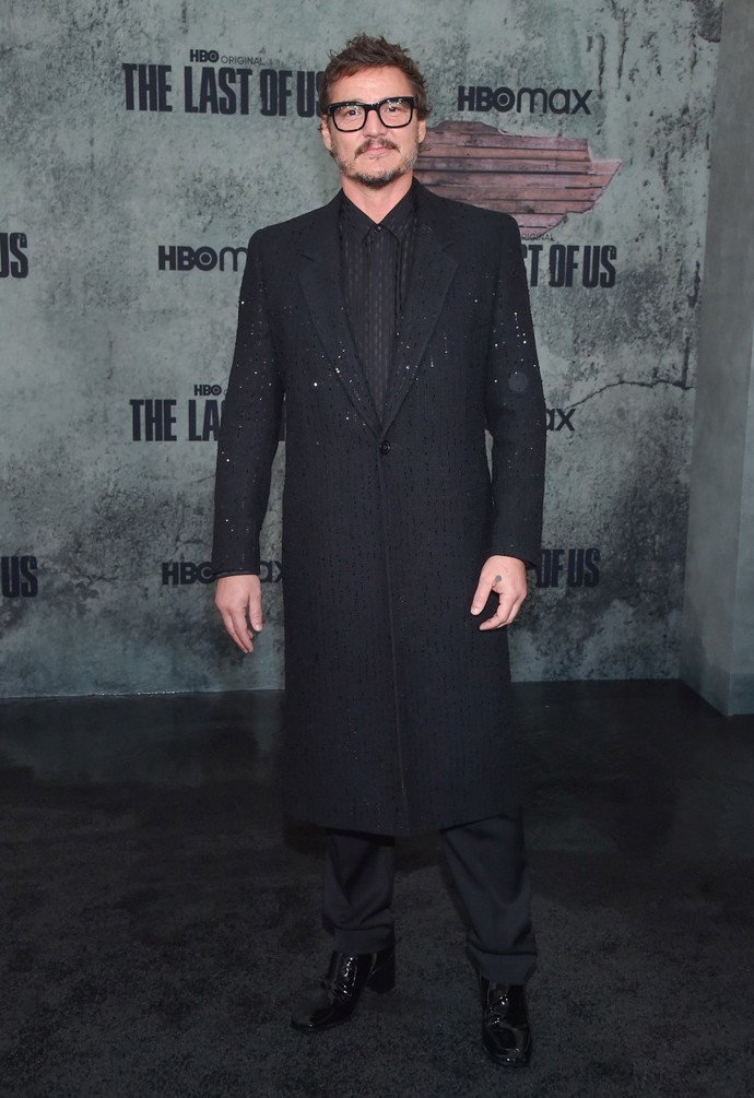 Pedro Pascal má vedle kardiganů velkou slabost i pro netradiční kabáty. Na prezentaci seriálu The Last of Us vynesl tento z dílny Yves Saint Laurent posetý flitry (114 000 Kč), klasickou košili z matného a lesklého hedvábí (30 600 Kč), černé kalhoty na míru (21 000 Kč) a černé boty na zip z lakované kůže (27 500 Kč). Vše YSL.