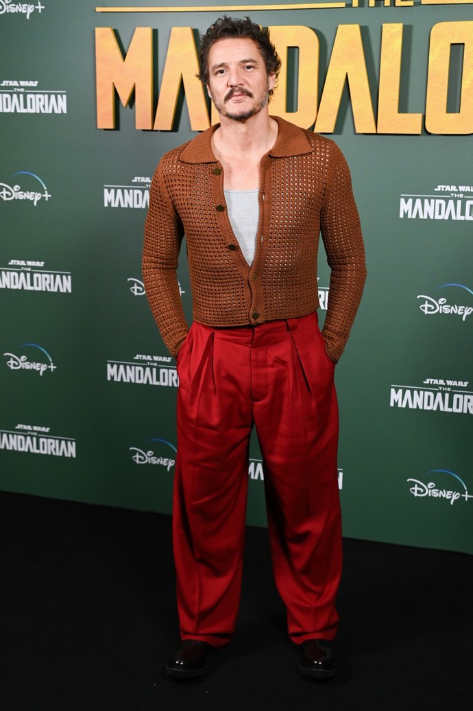 A jiný kardigan, tentokrát na prezentaci seriálu The Mandalorian. Tento síťovaný v barvě koňaku pochází z dílny Acne Studios (16 500 Kč). Pod ním měl Pedro šedé tílko Hanes (500 Kč) a outfit korunoval výrazně červenými kalhotami značky Acne Studios (10 300 Kč) a černými chelsea boots značky Adieu (10 500 Kč).