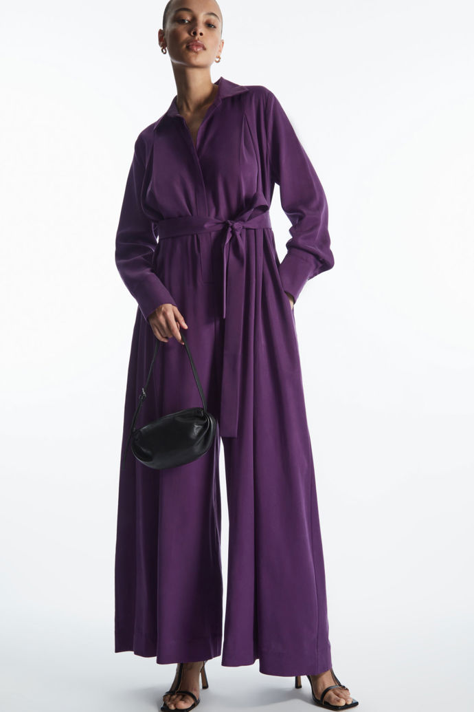 Temně fialový odstín podtrhuje elegantní střih kombinézy s límečkem a dlouhými rukávy z nabídky značky COS. 3 290 Kč
