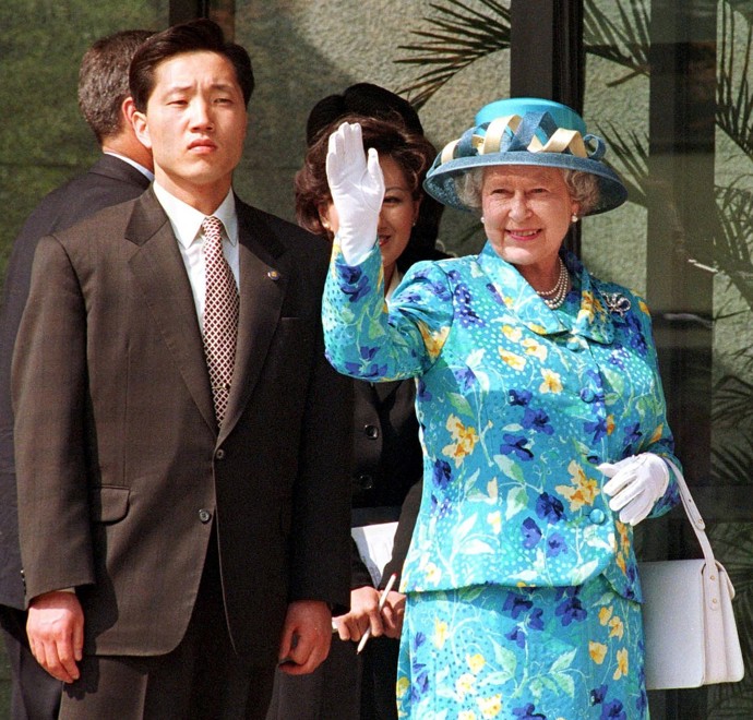 Královna Alžběta II. v rukavicích, které jí pro příležitost návštěvy Jižní Korey v roce 1999 doručil na motorce přímo do paláce manžel Genevieve Andrew Lawson.