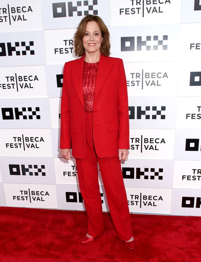 A s barvami umí Sigourney pracovat, i když jde o varianty tón v tónu. Zjevně ví, že vždy funguje zapojení různé textury ve stejných odstínech, příjemně tak zkombinovala saténový lesk střevíčků s bujaře třpytivými pajetkami, které zdobí jednoduchý top. To vše jako zpestření klasického saka a kalhot v červeném provedení.