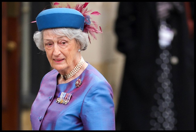 Bývalá dvorní dáma, Lady Susan Hussey, doplnila taftový kostým barevně sladěným toka kloboukem s pírky.