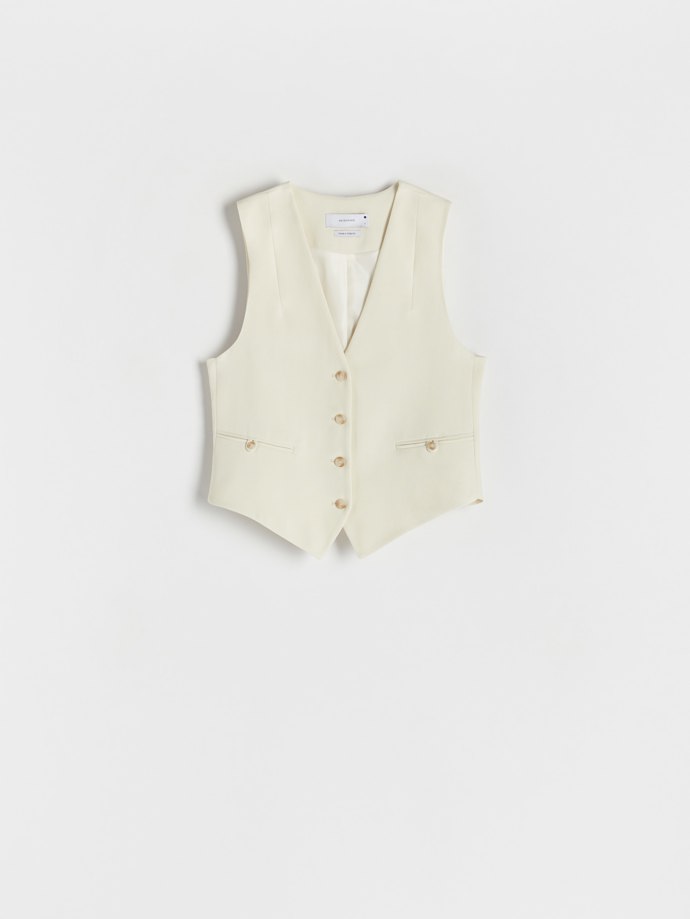 Zkrácená obleková vestička s propracovanými detaily ve smetanových tónech. (Reserved, 899 Kč)