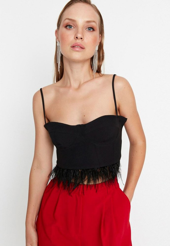 Peří už vedle okázalých rób zdobí také běžnější oděvy. (Trendyol, 899 Kč)