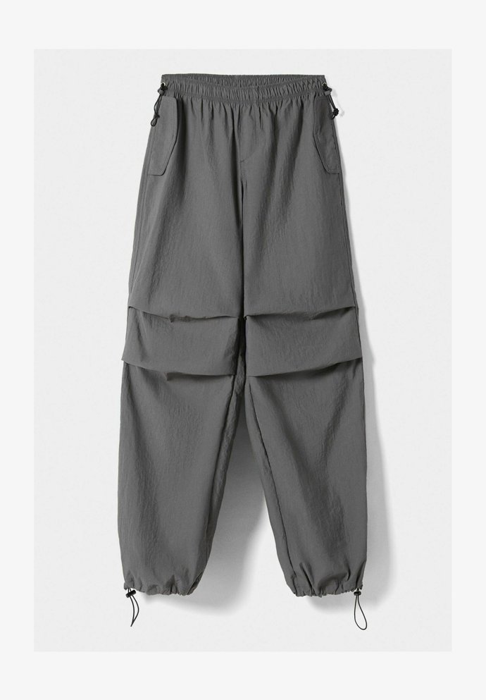 Kalhoty ze splývavého materiálu s nápadnými sklady na kolenou. (Bershka, 999 Kč)