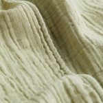 Detail mušelínového materiálu, typický svým prolamovaným, mačkaným, keprovým vzhledem.