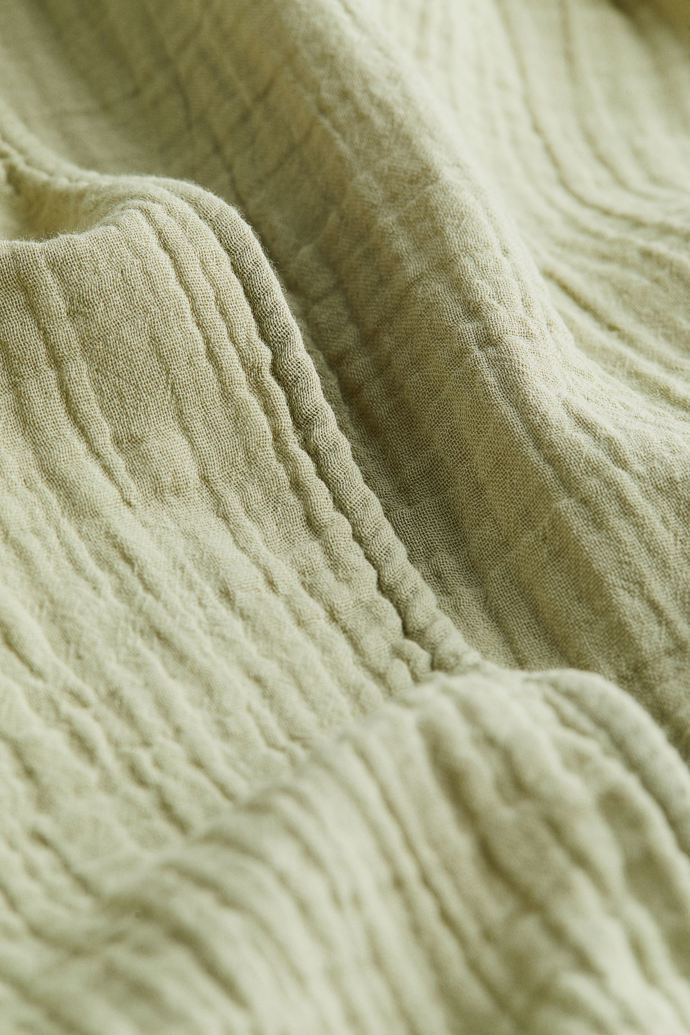 Detail mušelínového materiálu, typický svým prolamovaným, mačkaným, keprovým vzhledem.