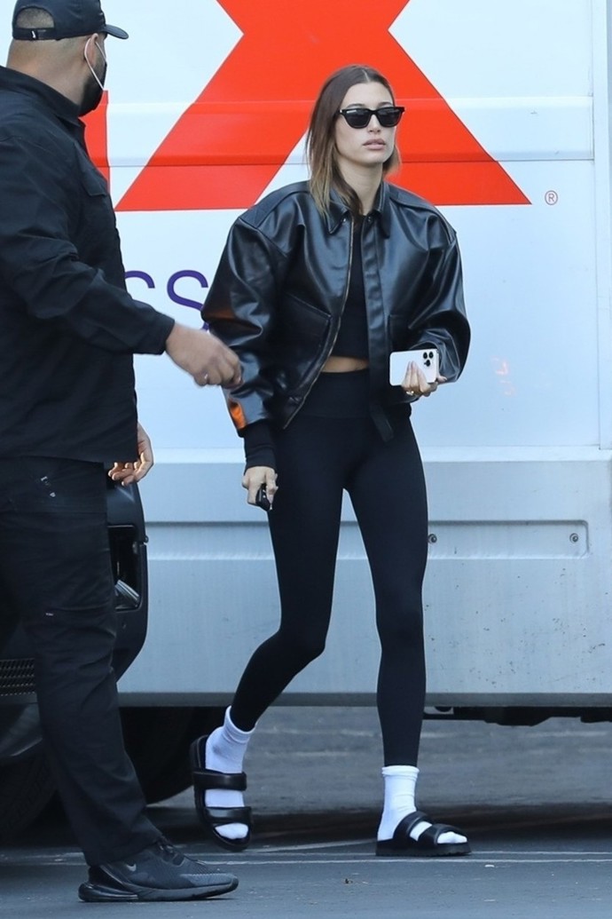 Hailey Bieber kožené pantofle sladila s krátkou bundou typu bomber. Bílé sportovní ponožky ale nemohly chybět.