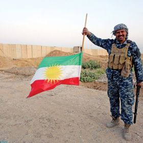 Voják s obrácenou kurdskou vlajkou.